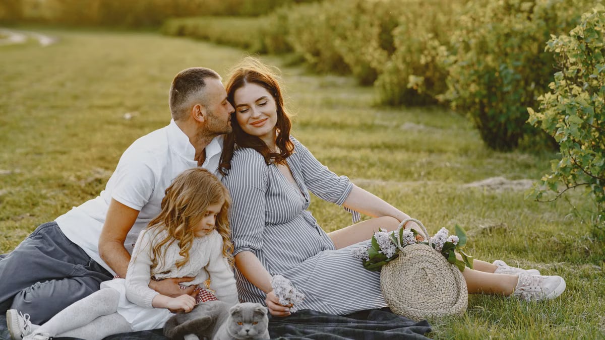 Family enjoying a joyful picnic in a sunny field with their pet cat, capturing a serene and loving moment.